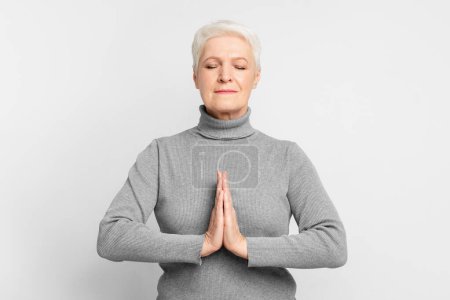 Die ältere Europäerin ist in Meditationspose und beschwört ein Gefühl von Spiritualität und Introspektion herauf, das auf s3niorlife Reflexion hinweist