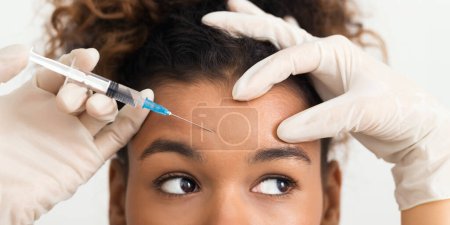 Photo for Cosmetic procedures. African-american woman getting botox injection in forehead - Royalty Free Image