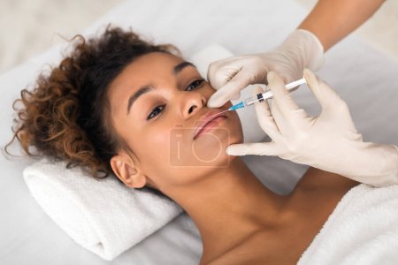 Téléchargez les photos : Cosmetologue faisant injection de beauté dans les lèvres féminines avec seringue - en image libre de droit