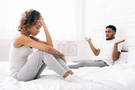 Foto de Pareja milenaria discutiendo en la cama. Frustrada novia negra pensando en problemas de relación, hombre culpándola - Imagen libre de derechos