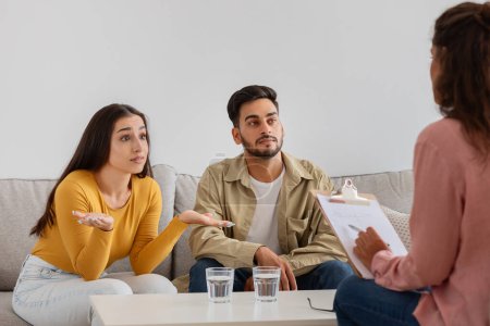 Esta imagen captura a una pareja joven que se ve desconcertada mientras habla con un terapeuta en una sesión, terapia familiar