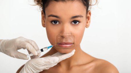 Téléchargez les photos : Augmentation des lèvres. Femme obtenant l'injection de lèvres et regardant la caméra à la clinique - en image libre de droit
