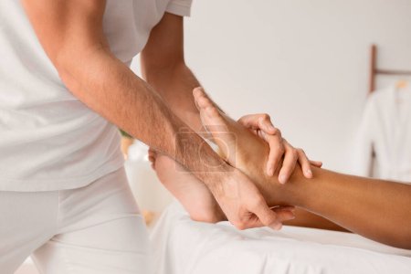 Téléchargez les photos : Vue détaillée d'un masseur mains comme ils massent habilement un pied de clients, soulignant la technique complexe et ambiance relaxante - en image libre de droit