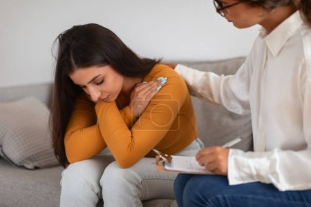 Terapeuta consoladora paciente joven ansiosa durante una sesión de terapia que muestra atención y apoyo
