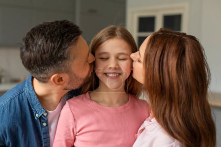 Parents show affection to their smiling daughter in a home setting, father and mother kissing girl, closeup