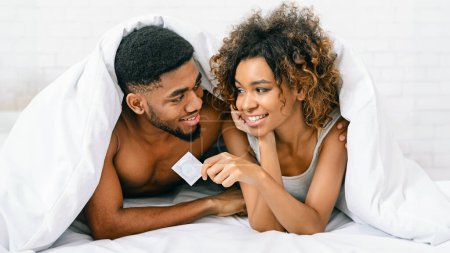 Foto de Concepto de sexo seguro. Manos masculinas y femeninas sosteniendo condón, primer plano - Imagen libre de derechos