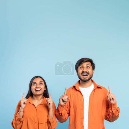 Foto de Hombre y mujer indios mirando hacia arriba, sus rostros reflejando asombro y curiosidad, sobre un telón de fondo azul - Imagen libre de derechos