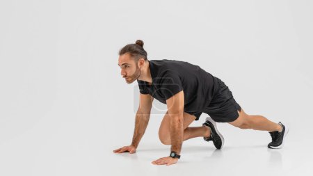 Seitenansicht eines fitten Kerls, der auf sauberem Hintergrund die richtige Ausfalltechnik demonstriert und sich dabei auf die Beinmuskulatur konzentriert