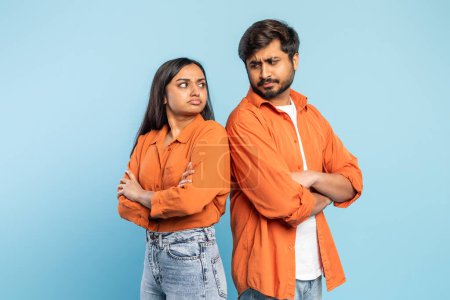 Indian man and woman facing away from each other with crossed arms, signaling a disagreement, against blue background