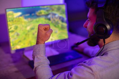 Foto de Un jugador con un puño apretado en un momento de triunfo o juego intenso, comprometido con la pantalla de la computadora - Imagen libre de derechos