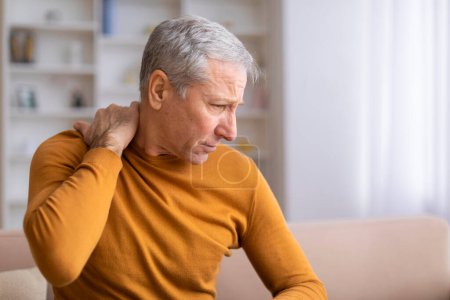 An older male individual experiencing discomfort in his shoulder, possibly indicative of a common age-related condition