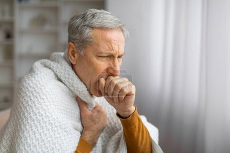 Ein kranker älterer Mann ist in eine Decke gehüllt, seine Haltung und sein Gesichtsausdruck deuten auf Krankheit oder Unwohlsein hin und stellen gesundheitliche Probleme dar