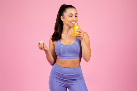 Una mujer en ropa deportiva decidiendo entre una píldora vitamínica y jugo de naranja natural