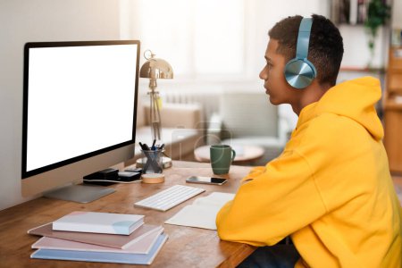 Une personne attentive travaille à son ordinateur dans une configuration confortable et organisée de bureau à domicile