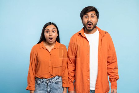 Téléchargez les photos : Expressive paire indienne affichant leur surprise et leur enthousiasme sur un fond bleu uni, parfait pour engager le contenu - en image libre de droit