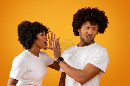 Foto de Afro americano millennial pareja tener lucha en amarillo studio fondo. Tipo negro molesto mostrando gesto de stop a su gritando y haciendo gestos novia o esposa. Crisis en el matrimonio, relaciones - Imagen libre de derechos