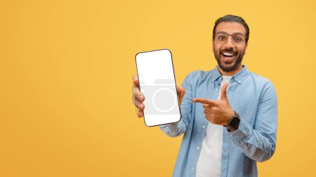 Happy eastern man with beard points to a blank smartphone screen suitable for app promotion