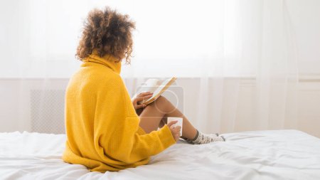 Foto de Mujer leyendo libro y disfrutando de café caliente, relajarse en el dormitorio - Imagen libre de derechos