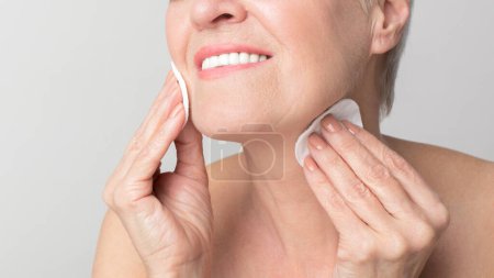 Téléchargez les photos : Portrait d'une femme européenne senior appliquant une crème faciale concentrée sur les soins de la peau et anti-âge, incarnant la vitalité s3niorlife - en image libre de droit