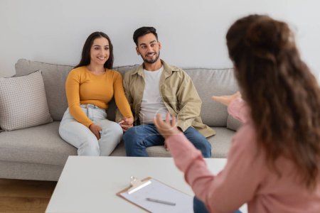 Photo for A young couple actively engages in conversation with their therapist during a family session to work on their marriage - Royalty Free Image