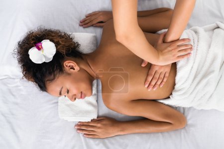 Téléchargez les photos : Femme recevant un massage du dos dans un salon de spa, relaxante avec les yeux fermés, vue sur le dessus - en image libre de droit
