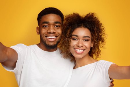 Photo for We are beautiful Happy young loving black couple making selfie, orange background - Royalty Free Image