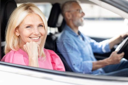 Téléchargez les photos : Une femme joyeuse est assise sur le siège passager d'une voiture, avec un homme conducteur au volant, à la fois content et détendu - en image libre de droit
