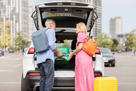 Photo for A retired couple puts their luggage into the trunk of their car, symbolizing the freedom and activity of senior life - Royalty Free Image