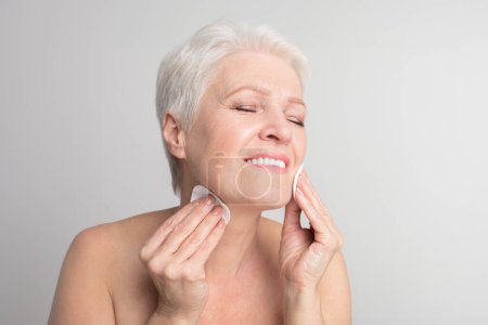 Um die Essenz der täglichen Selbstpflege zu erfassen, verwendet diese ältere Europäerin ein Wattepad für die Gesichtshygiene, ein Grundnahrungsmittel des s3niorlife