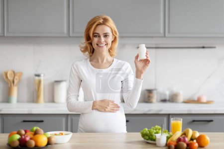 Foto de Una mujer europea, visiblemente embarazada, considera suplementos nutricionales en su cocina, rodeada de una variedad de opciones de alimentos saludables - Imagen libre de derechos