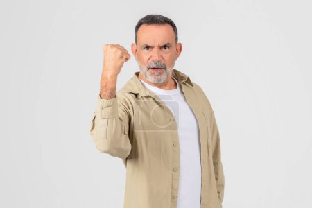 Photo for A firm and resolute elderly man clenches his fist, isolated on a white background, feeling angry, have fight - Royalty Free Image