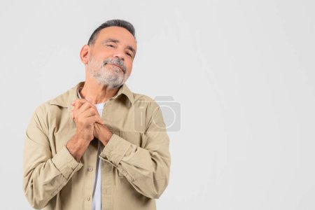 Photo for A senior man with a beard and a gentle smile looks joyfully upwards, standing isolated on a white background - Royalty Free Image