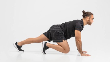 Photo for Determined man in a black outfit performing push-ups with an emphasis on form and strength over a clear background - Royalty Free Image