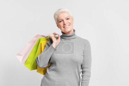 Foto de Contenido senior mujer europea con una colección de bolsas de compras de colores, disfrutando de su s3niorlife - Imagen libre de derechos