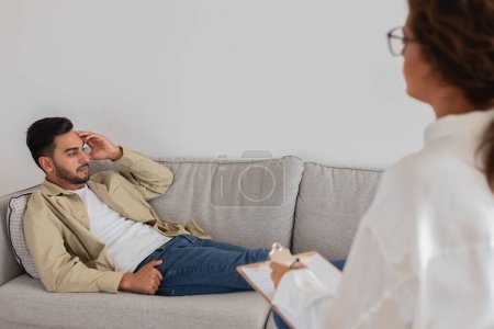 Ein junger Mann diskutiert in einer Therapiesitzung mit einer Therapeutin über seine Probleme. Konzept für psychische Gesundheit