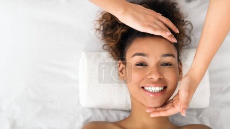Téléchargez les photos : Femme afro-américaine bénéficiant d'un massage du visage au salon de beauté, vue sur le dessus, espace de copie - en image libre de droit