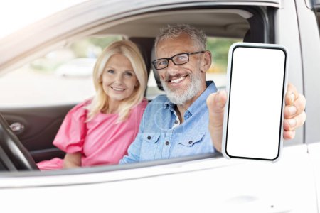Couple de personnes âgées en voiture tenant un smartphone d'appareil numérique à écran vierge, idéal pour l'utilisation de la technologie chez les retraités