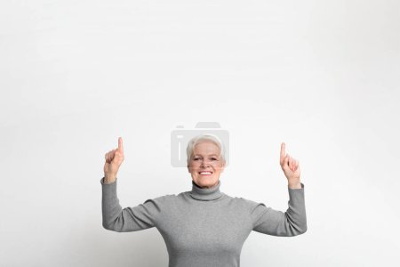 Lächelnde ältere europäische Seniorin zeigt nach oben, ihr Glück und ihre Freude spiegeln eine positive s3niorlife Erfahrung wider
