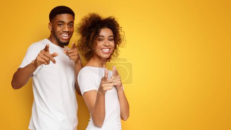 gotcha fröhlicher junger afrikanisch-amerikanischer Mann und Frau, der mit dem Finger in die Kamera zeigt, orangefarbener Studiohintergrund