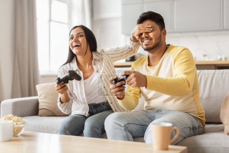 Téléchargez les photos : Cette image capture un couple indien heureux engagé jouant à des jeux vidéo, exprimant le plaisir dans un environnement familial millénaire - en image libre de droit