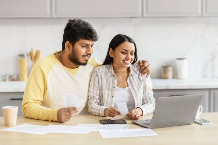 Photo for A millennial indian couple reviews their budget carefully in the kitchen, reflecting financial literacy and teamwork in their domestic partnership - Royalty Free Image