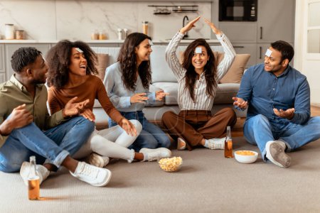 Une discussion animée entre jeunes amis multiraciaux, partageant des histoires et des rires autour d'un verre dans un confortable rassemblement à la maison