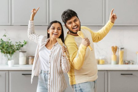 An enthusiastic indian couple, millennials at heart, uses kitchen utensils as microphones, dancing together with immense joy and a hint of playful spirit