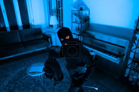 Photo for The image depicts a thief with a crowbar ready to break into or steal from the apartment, invoking a sense of imminent danger and theft at night - Royalty Free Image