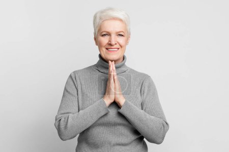Photo for A cheerful senior, elderly european woman with hands in namaste, reflecting positivity for s3niorlife - Royalty Free Image