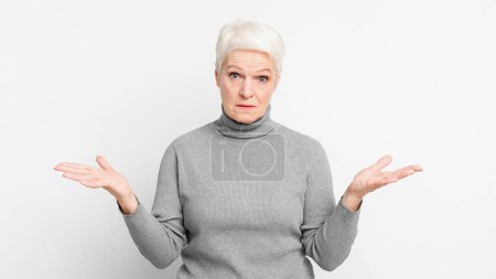 Eine ältere Europäerin schaut ratlos mit offenen Händen und drückt Unsicherheit oder Dilemma aus, die für s3niorlife-Entscheidungen relevant sind