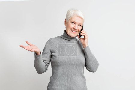 Téléchargez les photos : Femme européenne âgée engagée dans une conversation téléphonique avec un geste de la main, incarnant une communication active dans s3niorlife - en image libre de droit