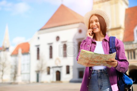 Photo for A millennial lady chats on the phone while holding a map outdoors, depicting a connected student navigating a European urban scape - Royalty Free Image