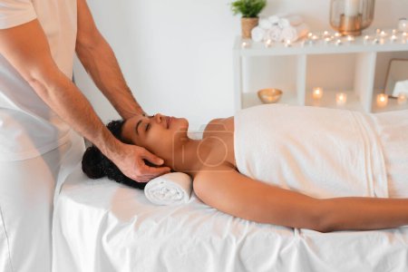 Showcasing African American lady in a relaxing massage session at a peaceful spa setting with candles