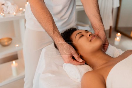 Téléchargez les photos : Un thérapeute expert donne un massage des épaules à une femme afro-américaine dans un cadre de spa serein, les gens apprécient le bien-être - en image libre de droit